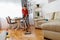 Male child vacuums the dust from the floor with a vacuum cleaner and listening to the music with headphones.