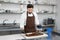 Male chocolatier uses a spatula to stir the tempered liquid chocolate on a granite table.