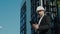 Male civil engineer contractor in safety helmet and jacket standing on construction site building and using mobile phone