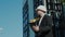 Male civil engineer contractor in safety helmet and jacket standing on construction site building and using mobile phone