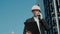 Male civil engineer contractor in safety helmet and jacket standing on construction site building and using mobile phone