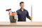 Male cleaner in a uniform posing with a bucket with cleaning supplies