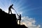 A male climber helps to climb the top of another person by throwing him a rope