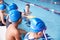 Male Coach In Water Giving Group Of Children Swimming Lesson In Indoor Pool