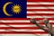 Male coarse hands chained in heavy iron chains against the background of the national flag of malaysia, concept of crime in the