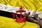 Male coarse hands chained in heavy iron chains against the background of the national flag of the state of Brunei, the concept of