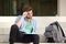 Male college student sitting outside thinking with notepad