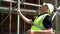 Male construction worker on building site inspecting and checking scaffolding for health and safety