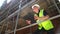 Male construction worker on building site writing on clipboard and talking on cell phone