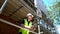 Male construction worker on building site writing on clipboard and talking on cell phone