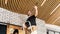 A male construction worker changes LED lamps on a pine plank wooden ceiling. Installation of a designer ceiling made of wooden