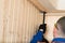 Male construction worker dismantling a wooden ceiling tearing boards off with a tool