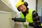 Male construction worker in hard hat drilling concrete wall