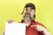 Male construction worker holding blank advertising board. Construction worker with poster. A rude, bearded, stern man in a red shi