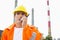 Male construction worker wearing reflective workwear communicating on walkie-talkie at site