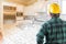 Male Contractor with Hard Hat and Tool Belt Looks at a Kitchen