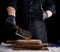 Male cook in black uniform and black latex gloves holds a large sharp meat knife over a cutting board