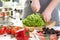 Male cook makes vegetable salad and cuts green lettuce leaves