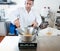 Male cook weighting honey with a spatula in commercial laboratory