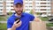 A male courier delivery man holds a box and uses a smartphone