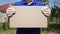 A male courier delivery man in medical gloves is holding a cardboard box