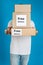 Male courier holding parcels with stickers Free Delivery on blue background