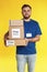 Male courier holding parcels with stickers Free Delivery on yellow background