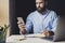 Male creative executive using smartphone for corporate projects. Man sitting at desk, using laptop and mobile phone for work