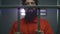 Male criminal in orange uniform and handcuffs stands in prison cell