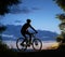 Male cyclist sitting on bicycle under beautiful night sky.