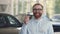 Male dealer standing at auto salon with keys in hands