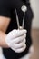 Male dentist with white gloves holding dental equipment - mirror and probe at the dental office