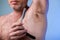 Male depilation. Young attractive man using razor to remove hair from his armpit. People and bodycare concept