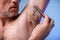 Male depilation. Young attractive man using razor to remove hair from his armpit. People and bodycare concept