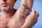 Male depilation. Young attractive man using razor to remove hair from his armpit. People and bodycare concept