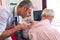 Male dermatologist examining senior patient with dermatoscopy