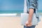 Male digital nomad hand holding laptop on the beach