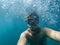 Male diver swims in the sea under water with a mask and snorkel is taking a selfie of your face