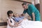 Male doctor check sickness of senior patient on patient bed, beside Lovely girl visit and encourage grandmother in hospital,