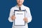 Male doctor holding clipboard with word UROLOGY on background, closeup