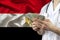 Male doctor holds in his hands a fan of banknotes dollars on the background of the silk national flag of Egypt, the concept of med