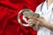 Male doctor holds in his hands a fan of banknotes dollars on the background of the silk national flag of Tunisia, the concept of