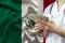 Male doctor holds in his hands a fan of dollars banknotes against the background of the mexico silk national flag, concept of