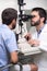 Male doctor ophthalmologist is checking the eye vision of handsome young man in modern clinic. Doctor and patient in