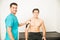 Male Doctor And Patient Smiling During Kinesiology Tape Therapy