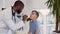Male doctor pediatrician, otolaryngologist, inspecting cute little boy throat.