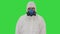 Male doctor in protective suit holding an digital infrared thermometer pointing with it to camera on a Green Screen