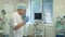 Male doctor putting surgical hat on while nurse washing her hands in a surgery room