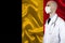Male doctor with stethoscope on the background of the silk national flag of Belgium, concept of national medical care, health,