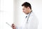 Male doctor with stethoscope writing prescription